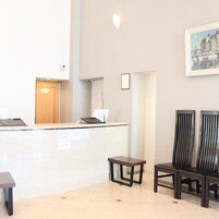 Un área de recepción con mostrador, una mesa pequeña, dos sillas y un cuadro en la pared.