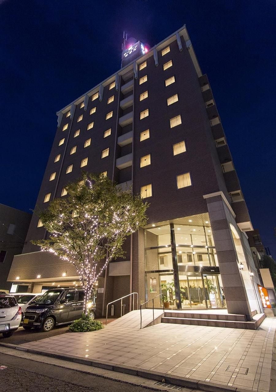 A multi-story hotel with a modern design, featuring a prominent entrance with glass doors and a well-lit facade.