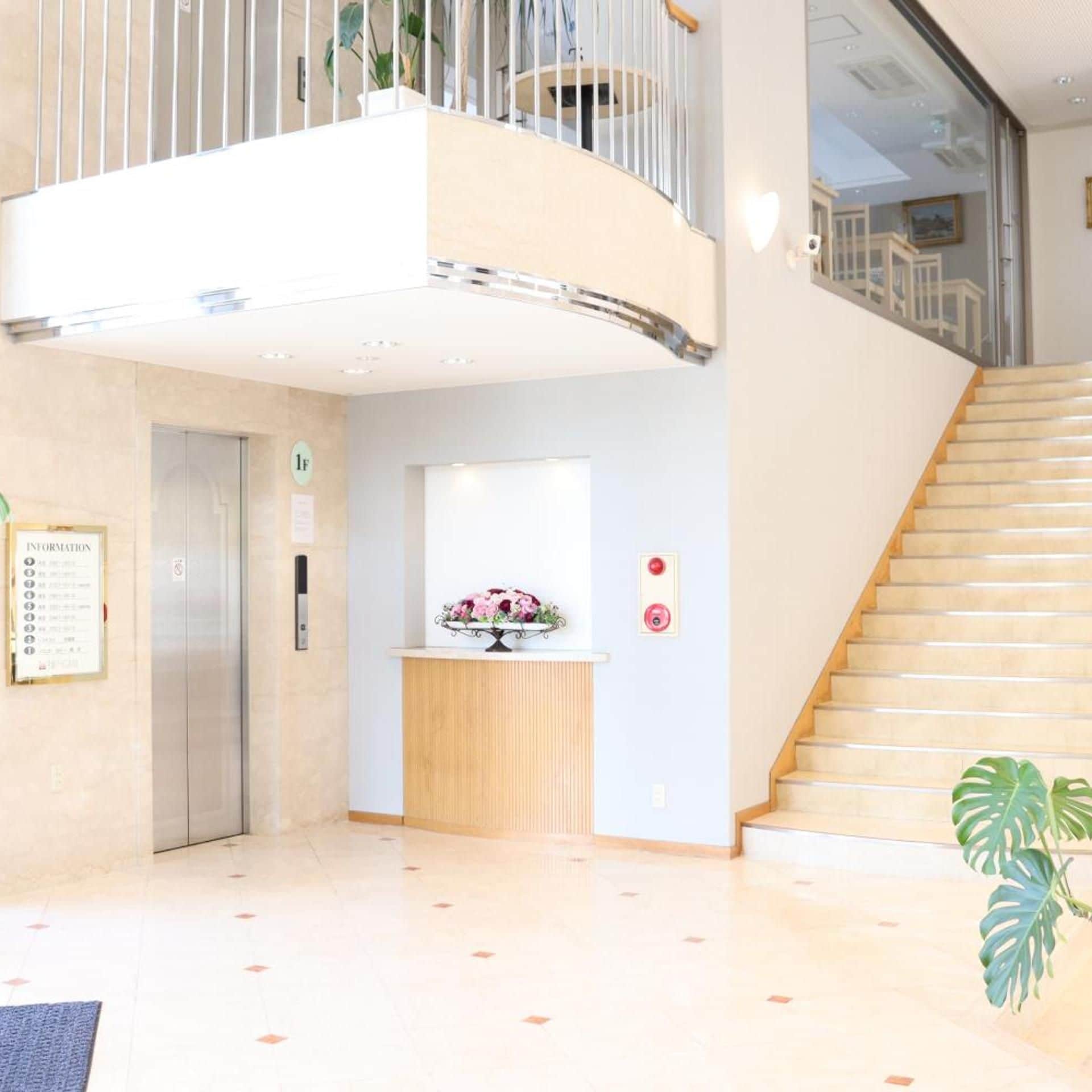 Un hall d’hôtel avec un comptoir d’accueil, un escalier et un ascenseur.