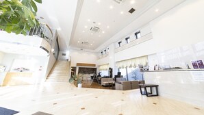 En rummelig lobby med højt til loftet, en trappe og en reception.