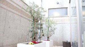 En moderne bygning med en betonfacade og et vindue. Der er plantede blomsterkrukker foran bygningen.