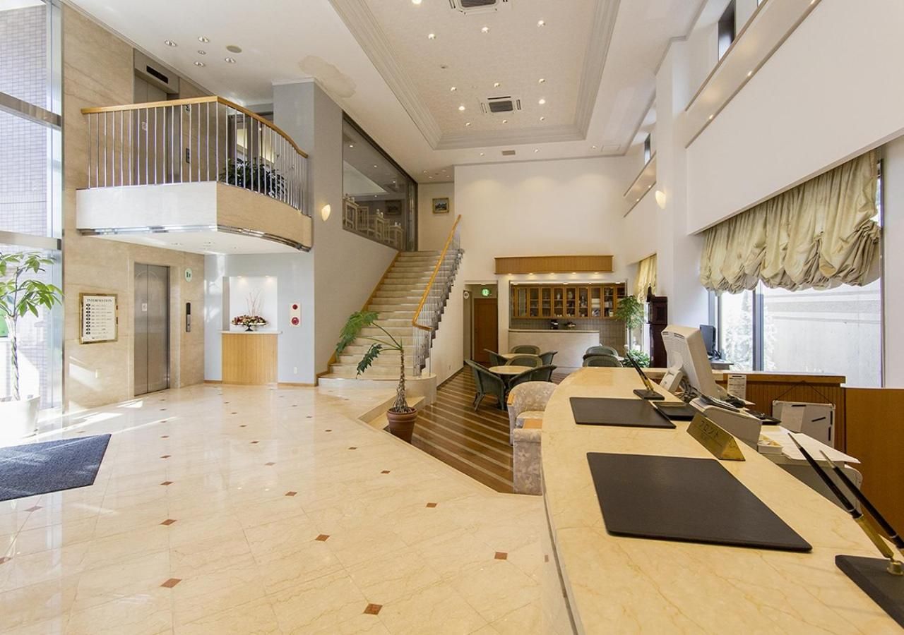 A spacious lobby with a reception desk, seating area, and a staircase leading to an upper level.