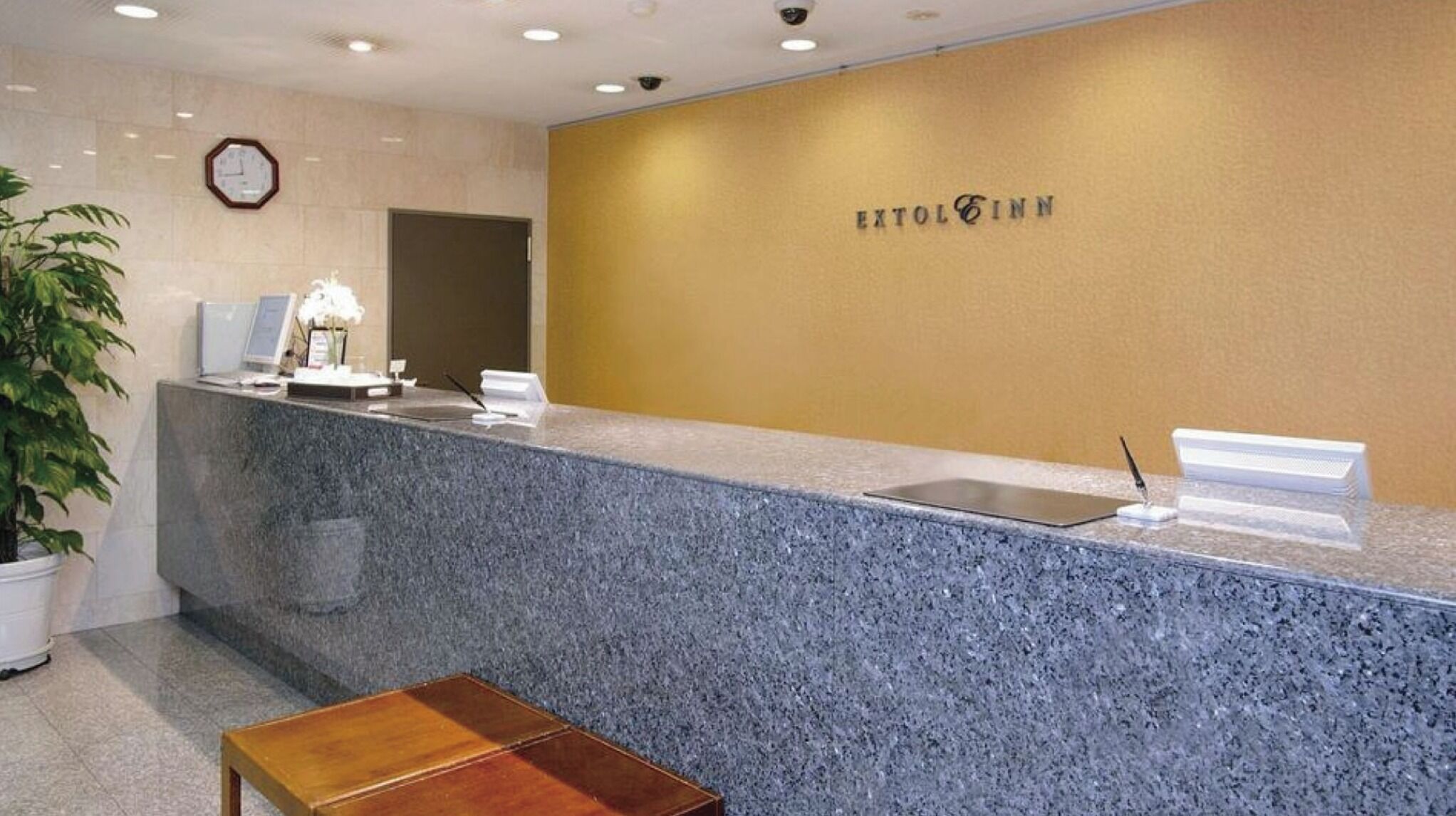 A reception desk with a clock, a plant, and a sign reading 'EXTOL INN'.