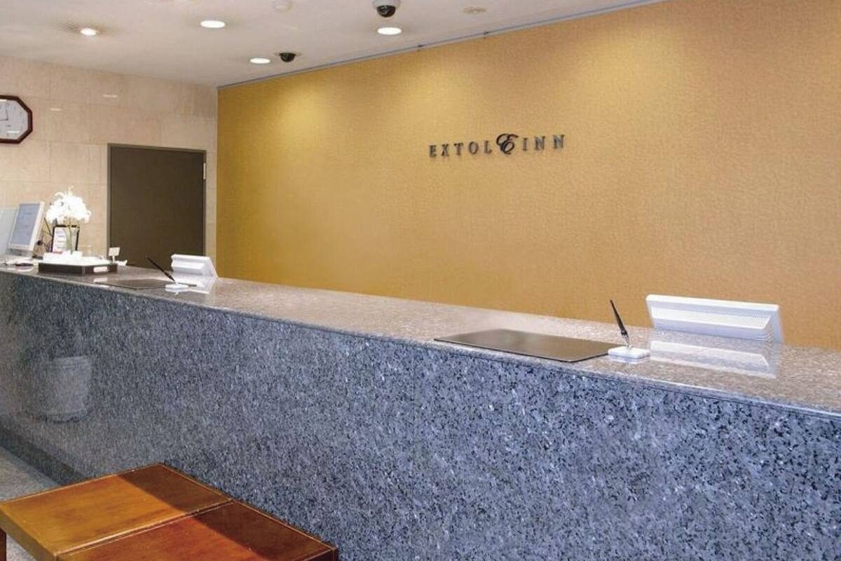 Un mostrador de recepción con un reloj, una planta y un cartel que dice 'EXTOL INN'.