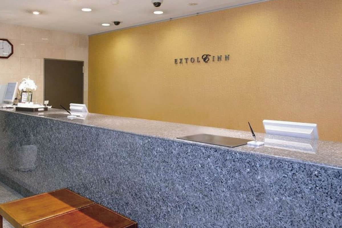 Un mostrador de recepción con un reloj, una planta y un cartel que dice 'EXTOL INN'.