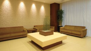 A modern lobby with two sofas, a coffee table, a large potted plant, and a textured wall. - Ab Hotel Nagoya Sakae (Nagoya)