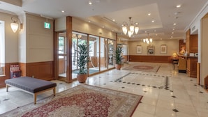 A spacious lobby with a bench, potted plants, a patterned rug, and a reception desk. - Hotel Gimmond Kyoto (Kyoto)