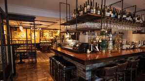 A bar area with a long counter, multiple stools, and shelves stocked with bottles and glasses. - Hotel Gimmond Kyoto (Kyoto)