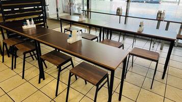 A restaurant with long wooden tables and benches, arranged in a spacious layout.