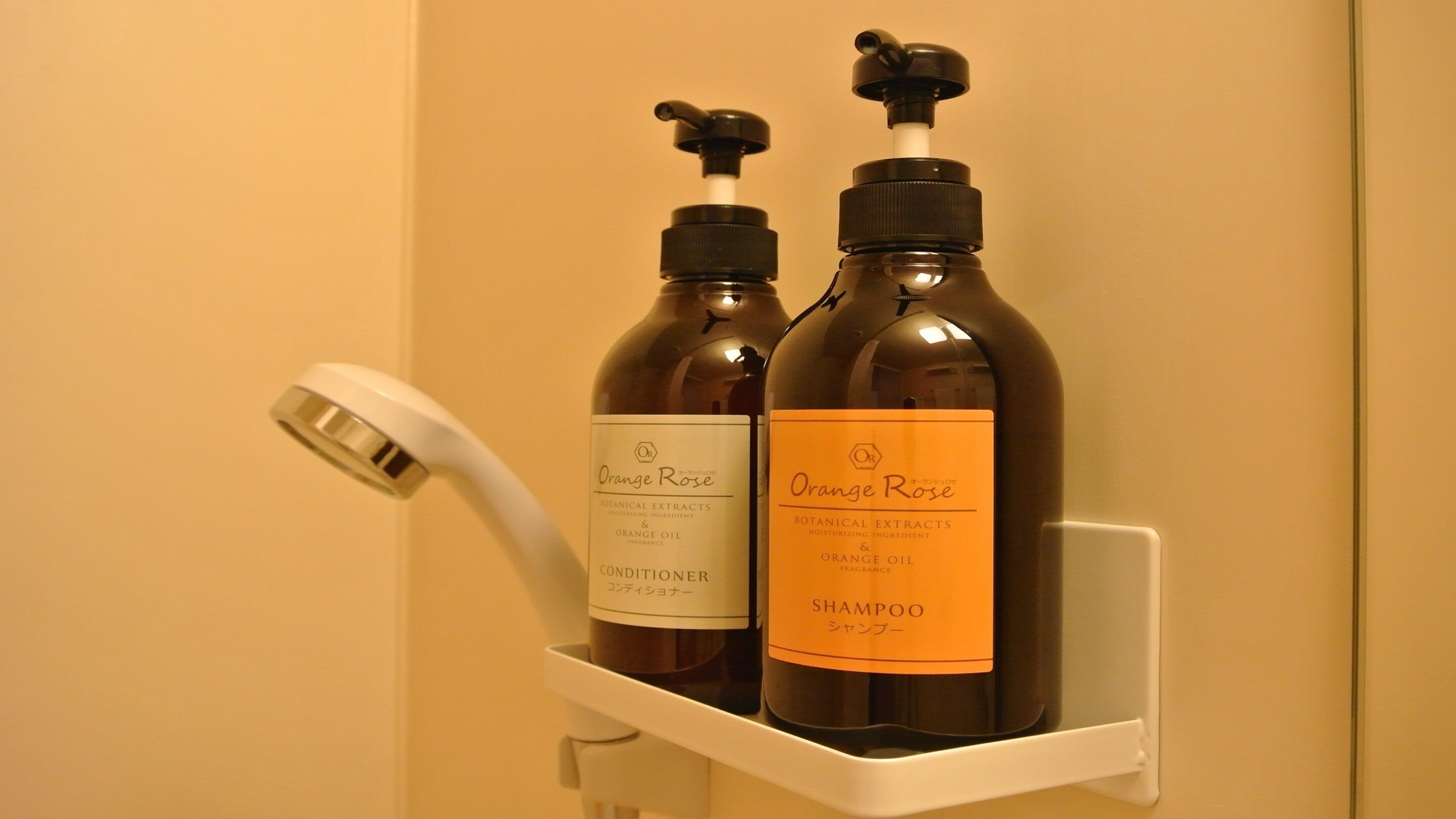 Two bottles of Orange Rose products on a white shelf in a bathroom.