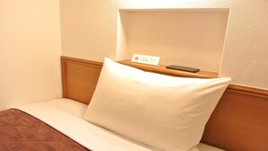 A hotel room with a bed, a pillow, a bedside table with a remote control, and a no-smoking sign. - R-bend Hotel ATSUGI (Atsugi)