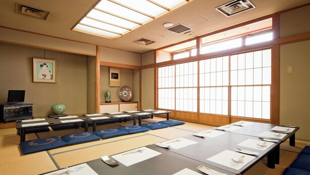 A traditional Japanese-style room with tatami mats, a long table with papers, and a large window with shoji screens. - Mimatsu Hotel (Mito)