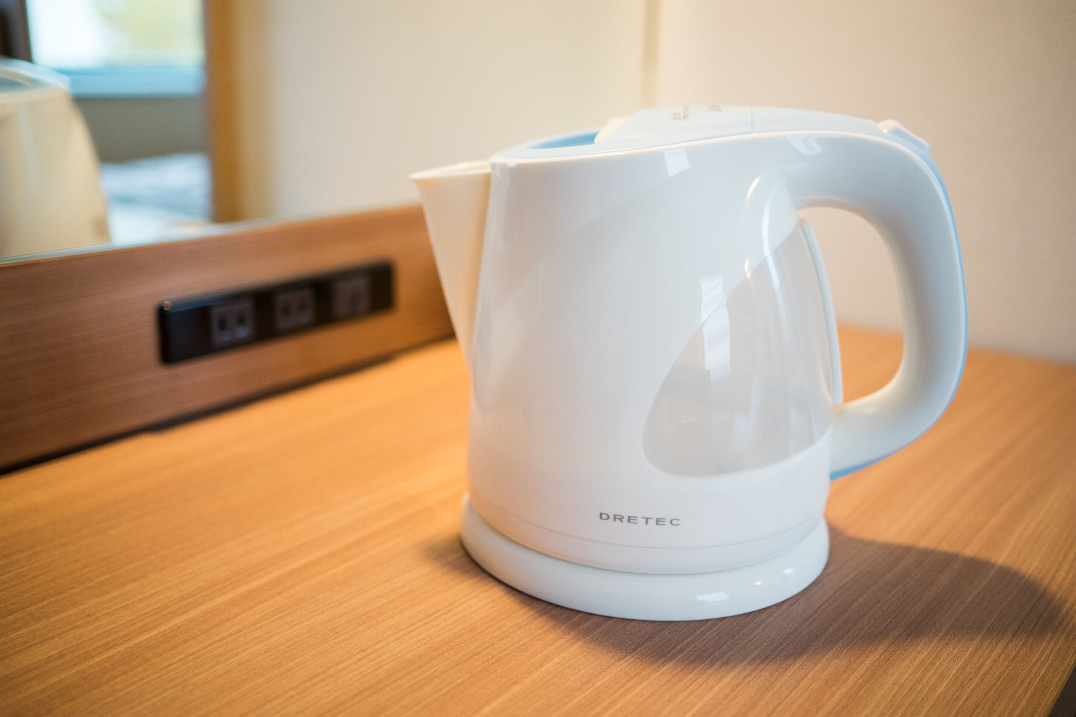 A white electric kettle with the brand 'DRETEC' on a wooden surface.