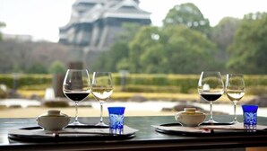 Un tavolo con bicchieri di vino e una ciotola, con vista su un castello tradizionale giapponese.