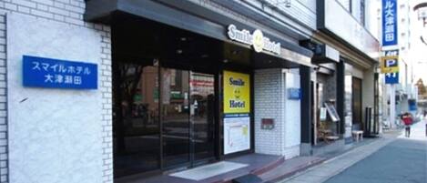 A hotel with a sign reading "Smile Hotel" and a blue sign indicating its location.