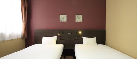 A hotel room with two single beds, a wooden headboard, a nightstand, and two wall-mounted lamps.