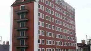 Un edificio de varios pisos con fachada roja y marcos de ventanas blancos.