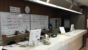 Mostrador de recepción de hotel con encimera de mármol, un reloj y un cartel que indica los horarios de registro de entrada y salida.