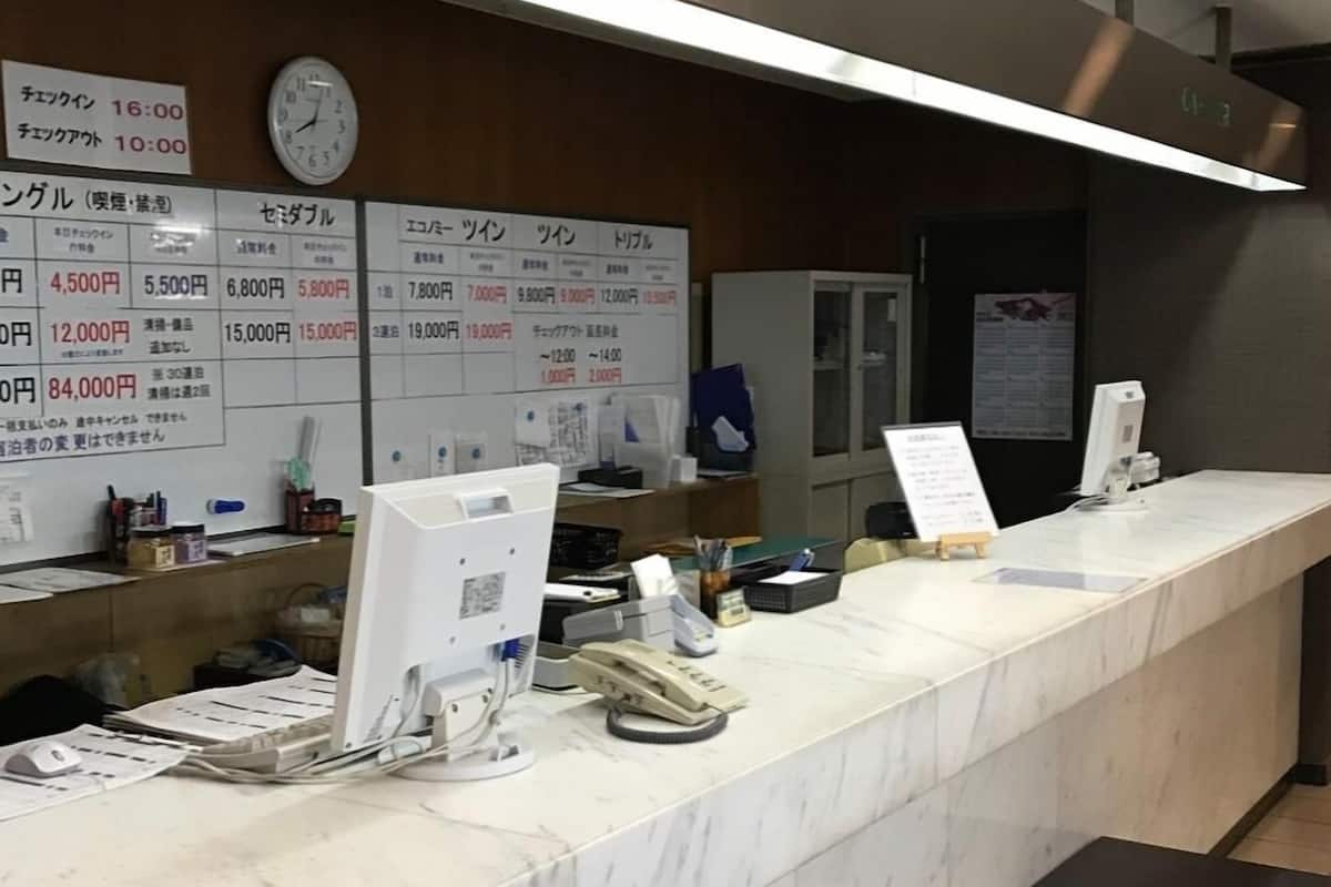 A reception desk with a marble counter, a computer, and a wheelchair.