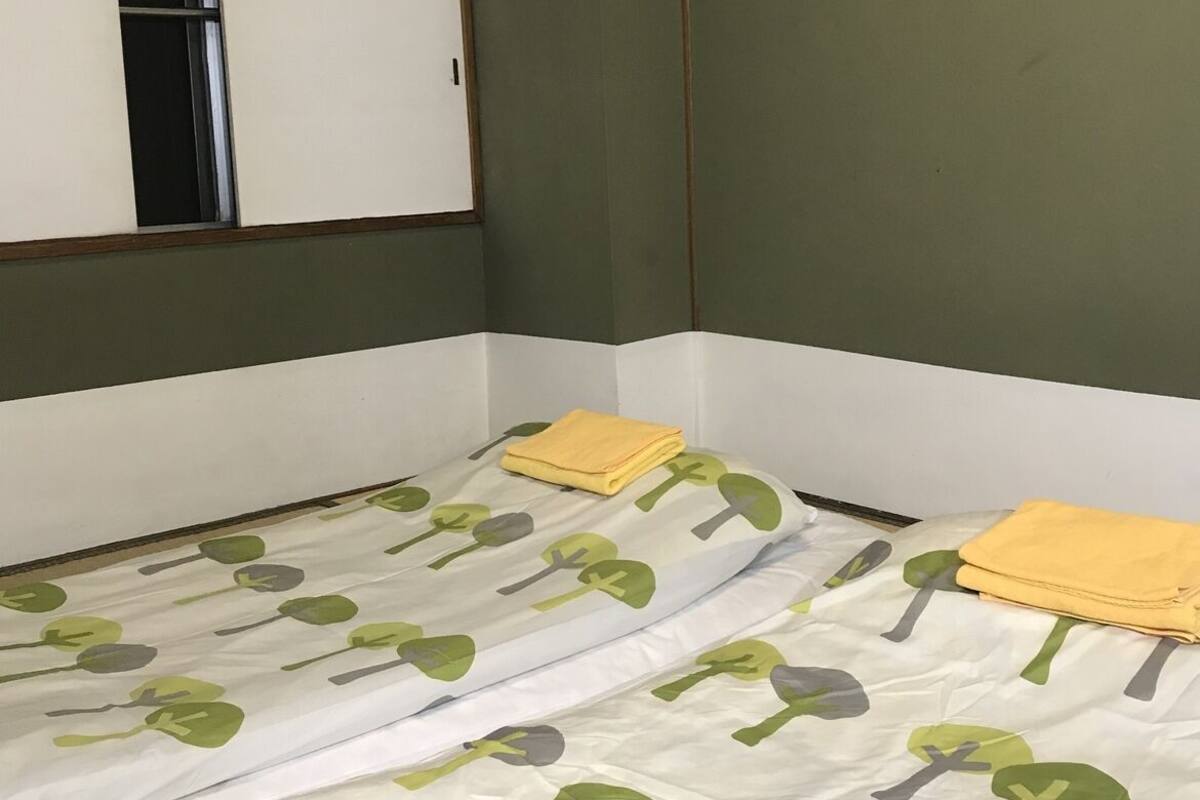 A room with a bed, a window, and green walls.