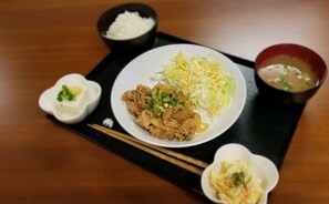 A plate of food with shredded cabbage, a bowl of soup, and a small dish of sauce on a black tray.