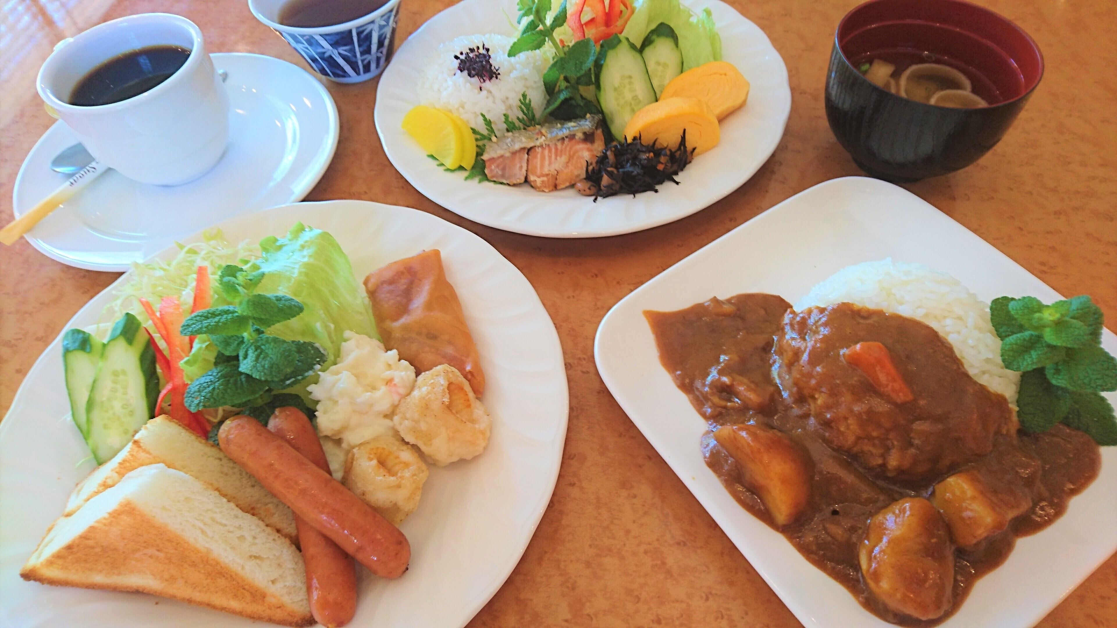 Una mesa con platos de comida, una taza de café y un tazón de sopa.