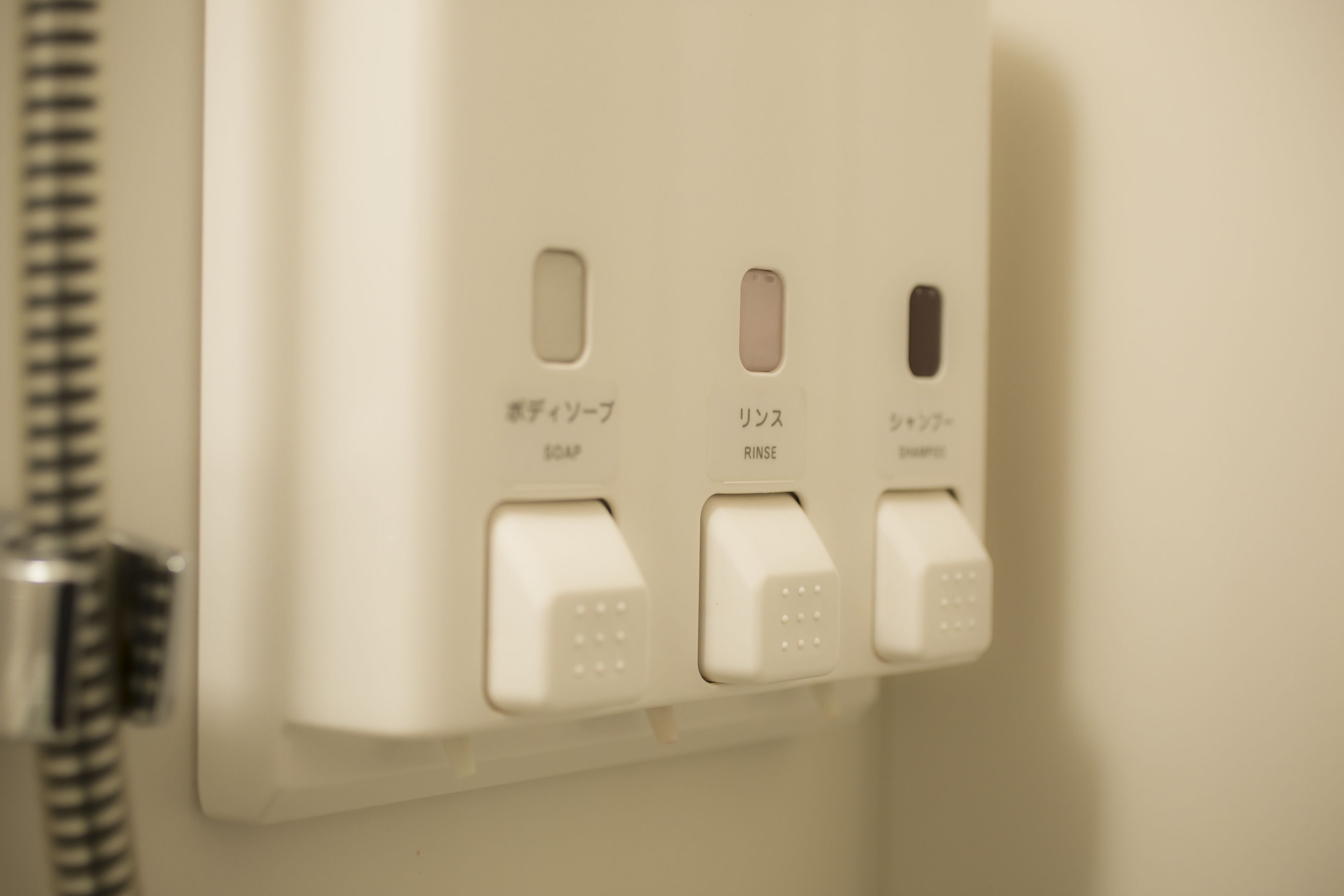 Ein Bedienfeld im Badezimmer mit Beschriftungen für Warmwasser, Spülen und Kaltwasser.