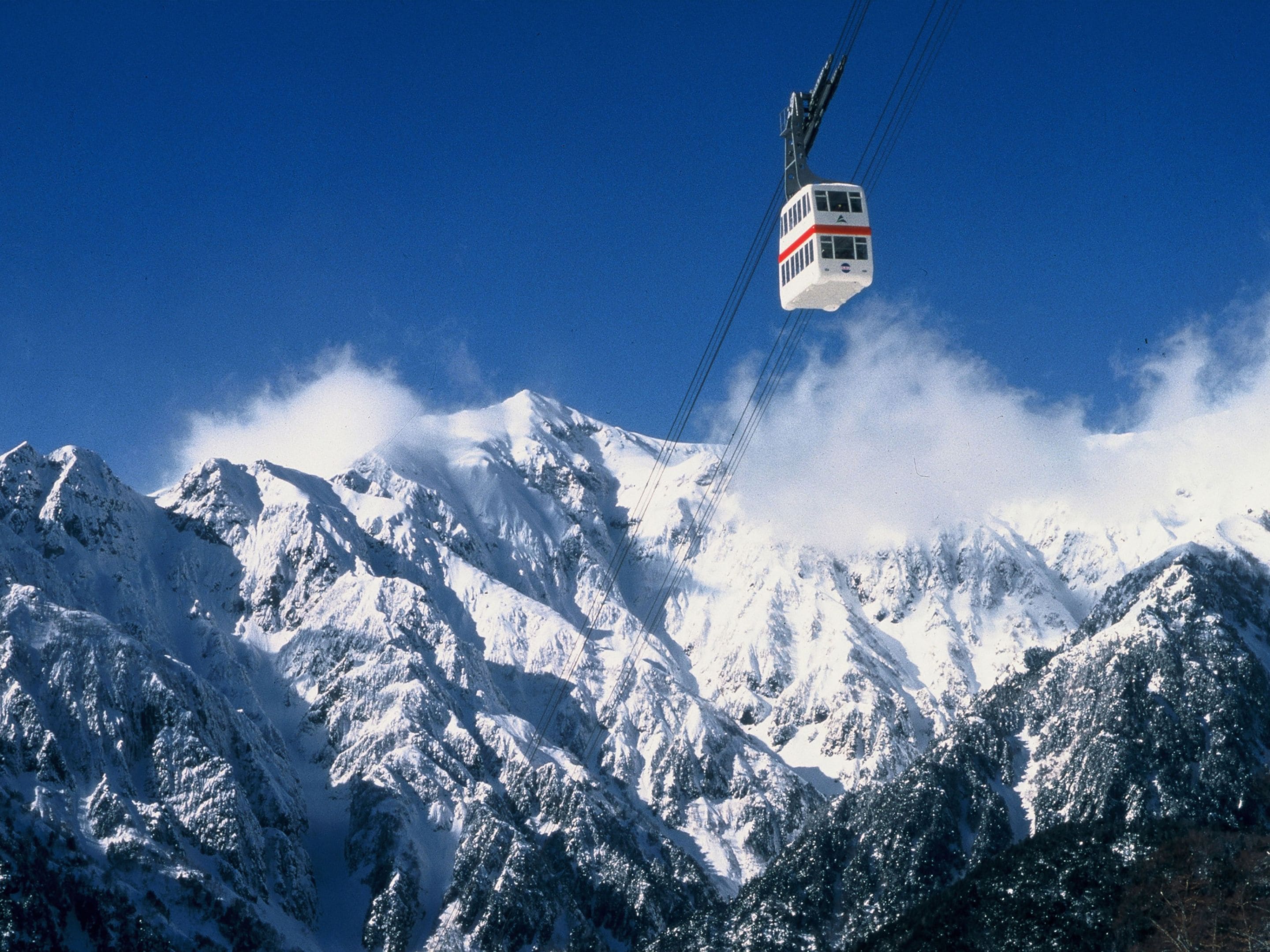 Un teleférico asciende una montaña cubierta de nieve.