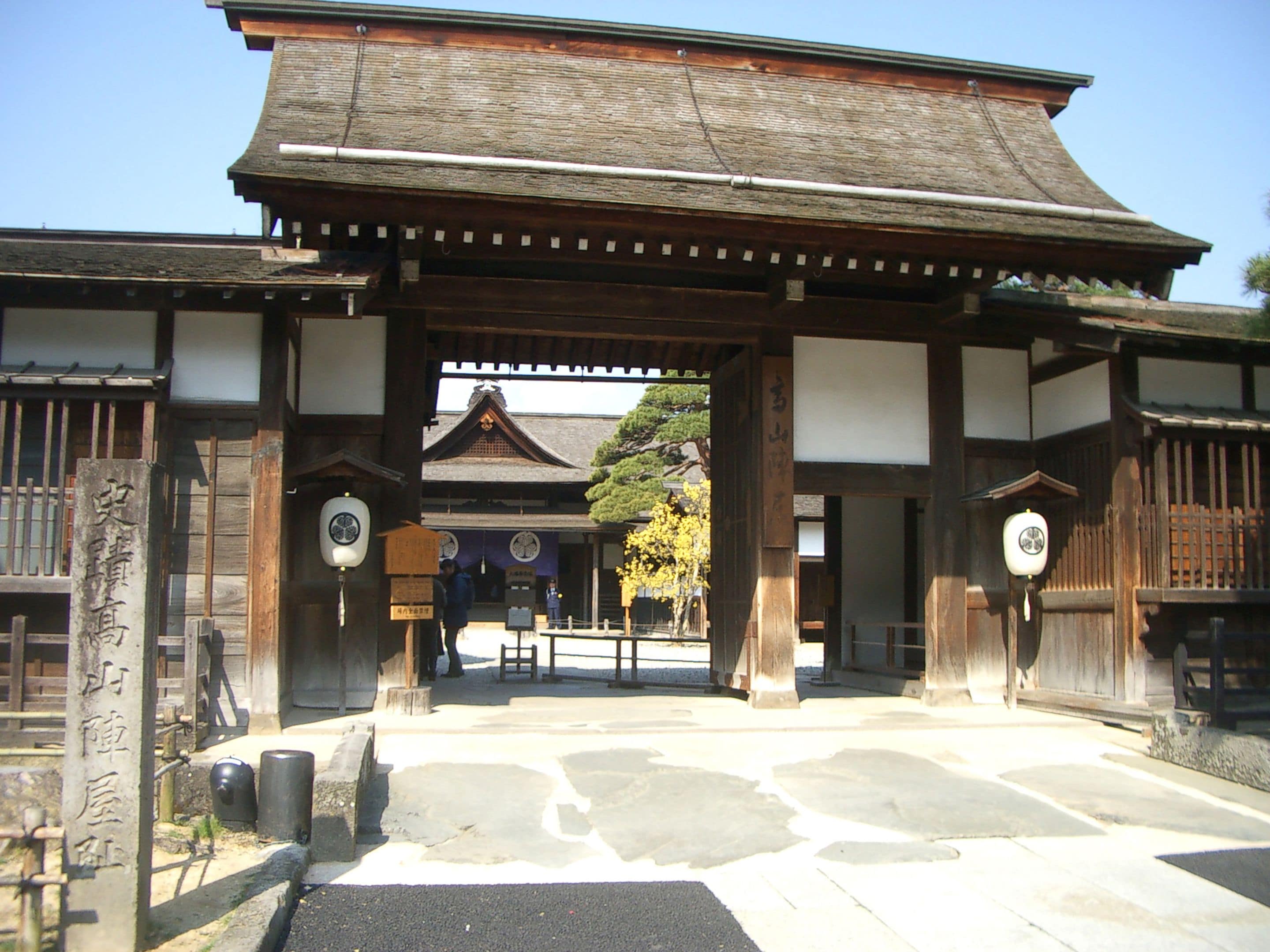 A traditional Japanese gate with wooden pillars and a tiled roof.