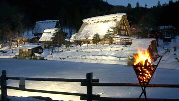 A snow-covered village with traditional wooden houses and a fire burning in the foreground.