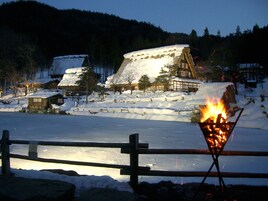 Un pueblo cubierto de nieve con casas de madera tradicionales y un fuego ardiendo en primer plano.