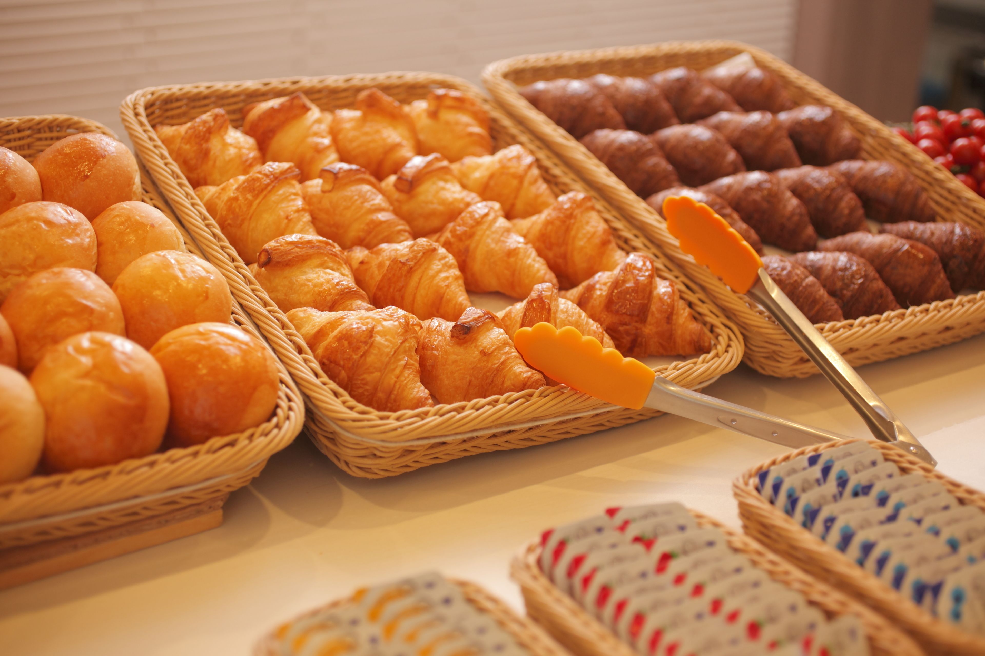 A variety of baked goods displayed in wicker baskets, including croissants and rolls.