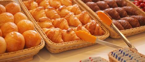 A variety of baked goods displayed in wicker baskets, including croissants and rolls.