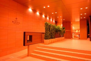 A hotel lobby with a modern design, featuring a staircase, potted plants, and a sign for the SPA HOTEL ALPINA. - Spa Hotel Alpina Hidatakayama (Takayama)