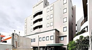 Ein mehrstöckiges Gebäude mit einer glatten Fassade, Balkonen und einer grünen Markise.