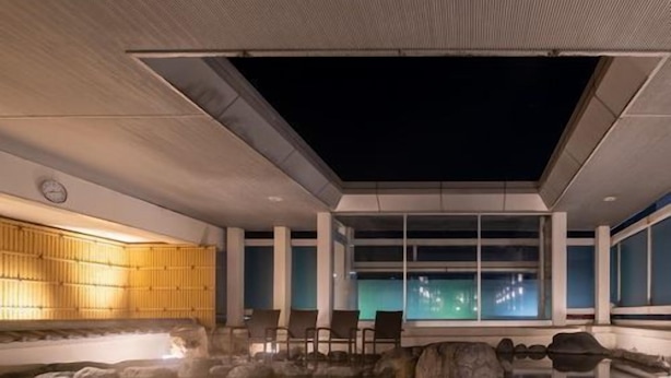 Zona de aguas termales con asientos y vistas al cielo nocturno.