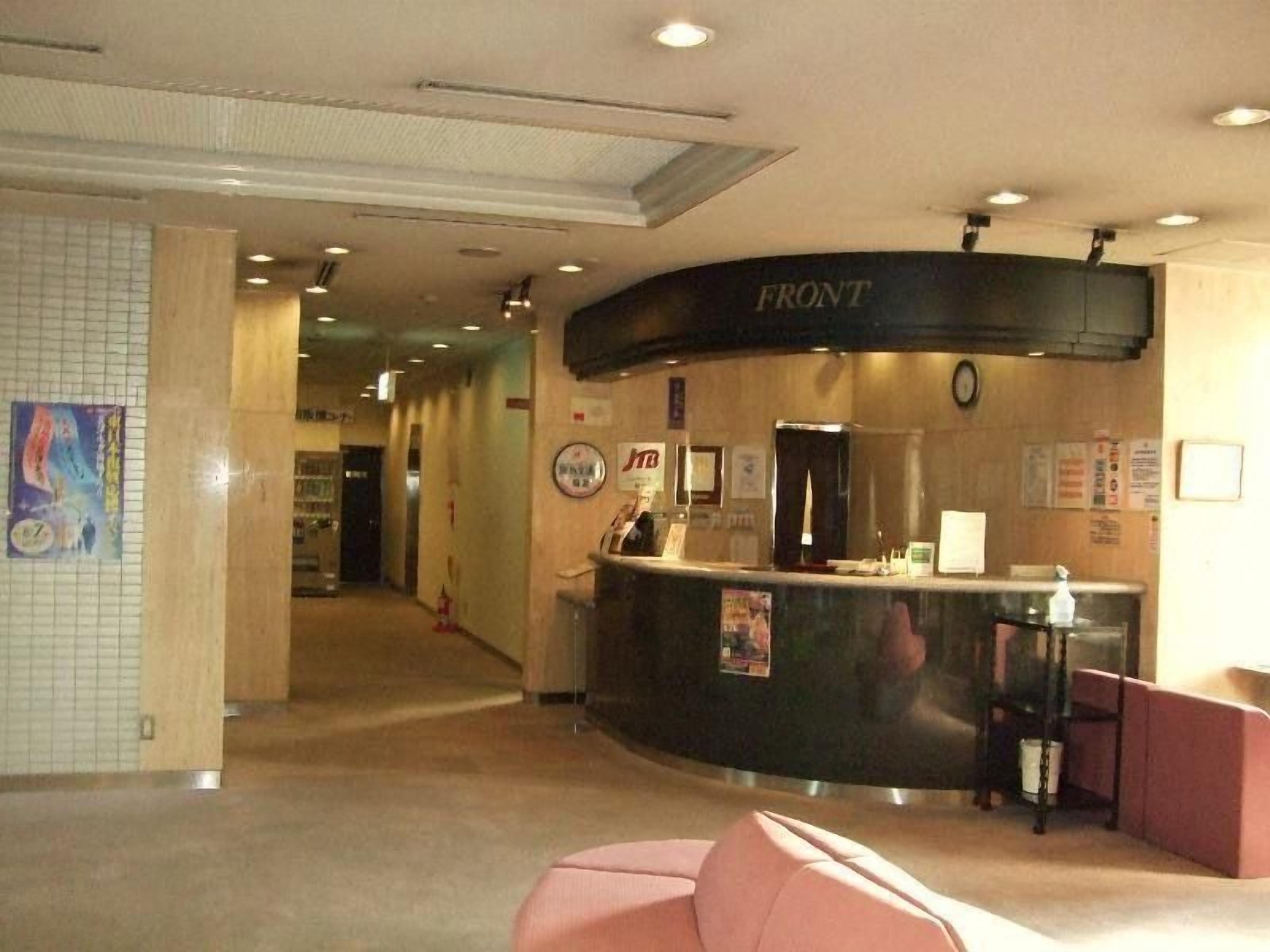 A hotel reception area with a curved counter, a clock, and a poster on the wall.