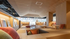 Un interior moderno con una zona de estar central, techo de madera y obras de arte en las paredes.