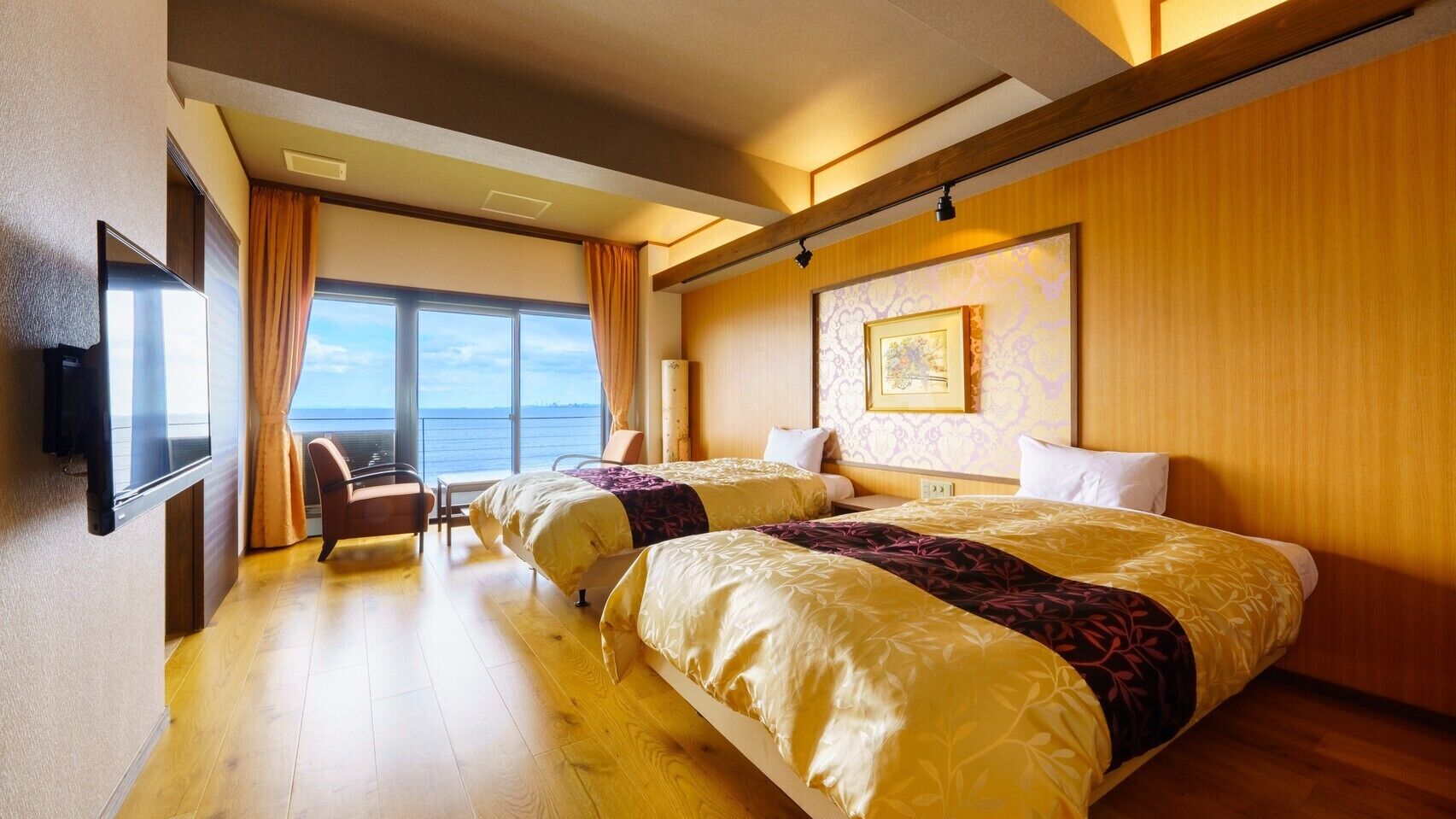 Une chambre d’hôtel avec deux lits, une télévision, une chaise et une grande fenêtre donnant sur un beau paysage.
