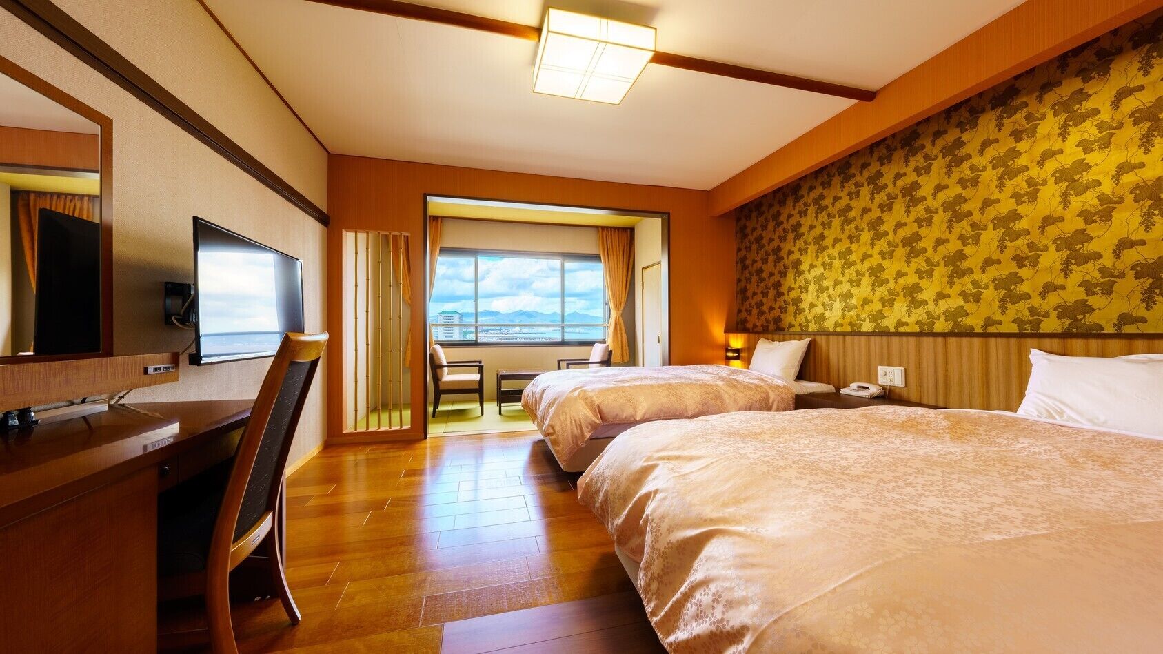 Quarto de hotel com uma mesa, duas camas, televisão e vista para a cidade.