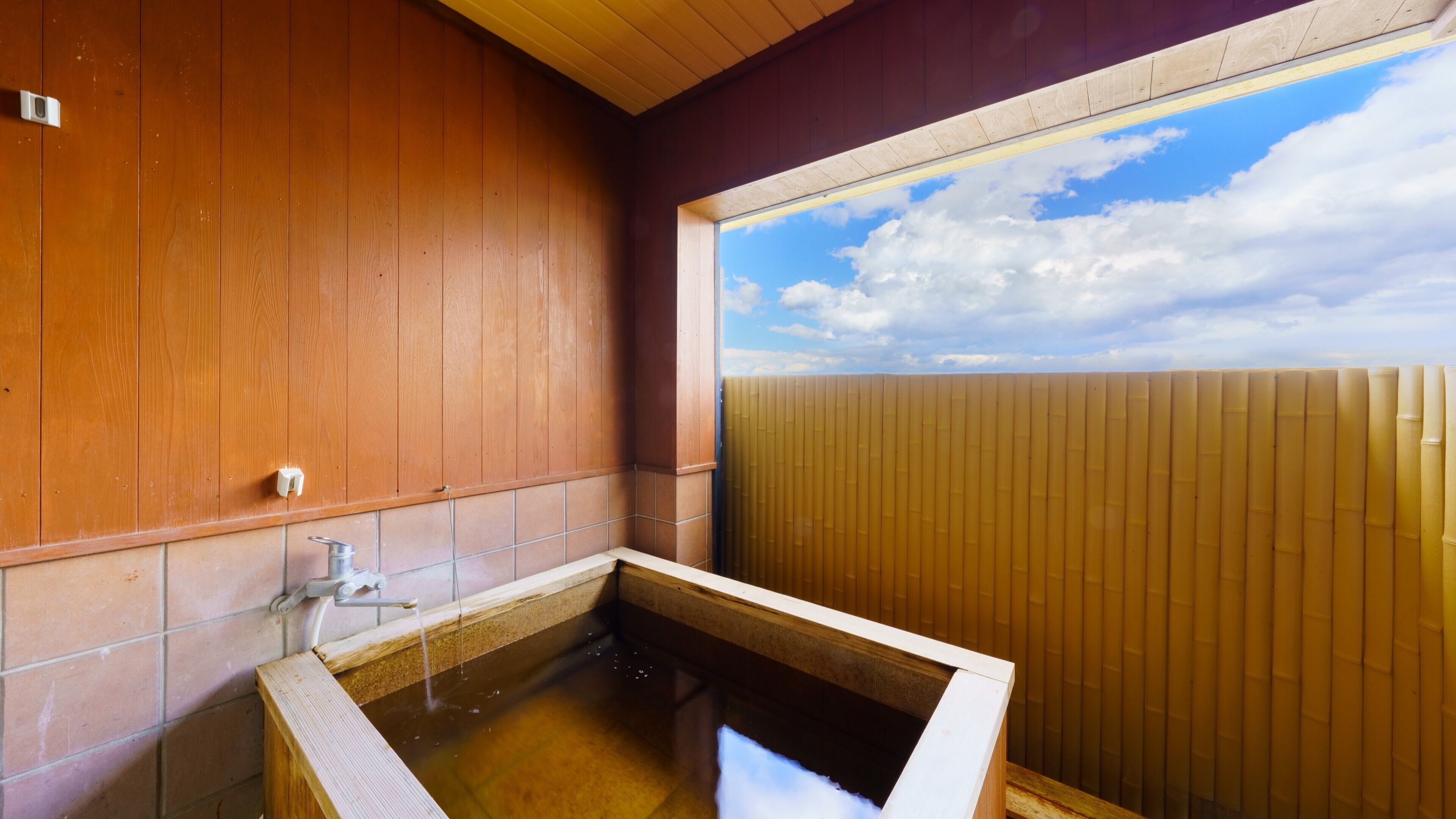 Un intérieur en bois avec une baignoire, une fenêtre et une vue sur le ciel.