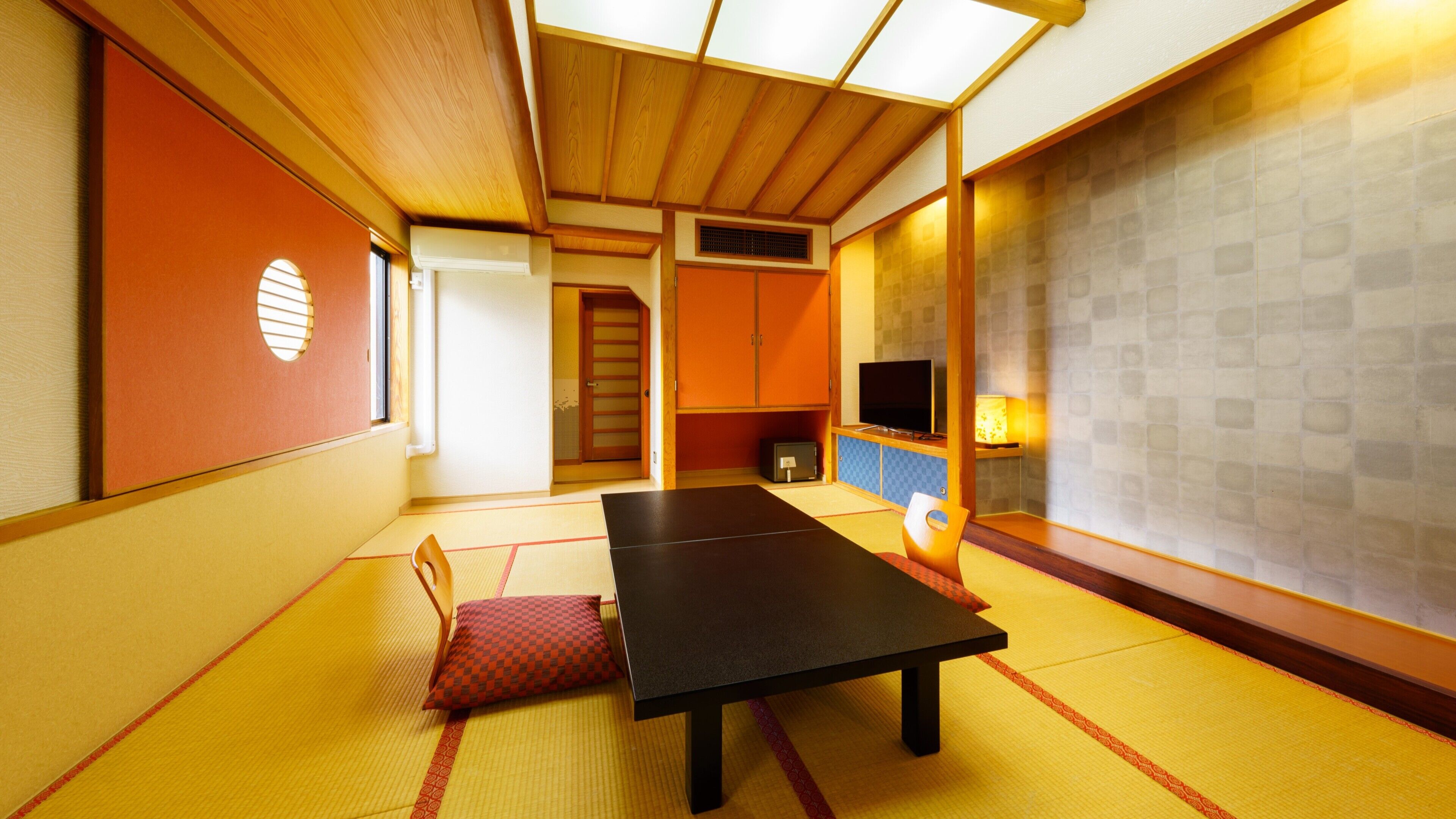 Une pièce de style japonais traditionnel, avec un sol recouvert de tatamis, une table basse, un téléviseur et des portes coulissantes.