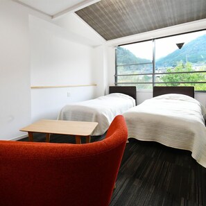A room with two beds, a small table, and a red chair. - Ryokan Furuyu Onsen Ogiya (SAGA SHI)