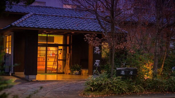 A traditional Japanese building with a tiled roof, a wooden entrance, and a sign with Japanese characters. - Ryokan Furuyu Onsen Ogiya (SAGA SHI)