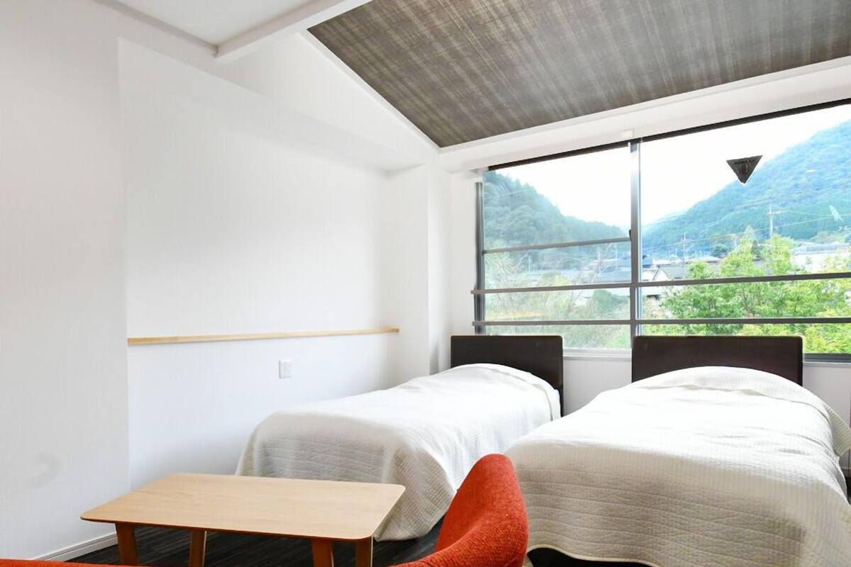 A room with two beds, a small table, and a red chair.