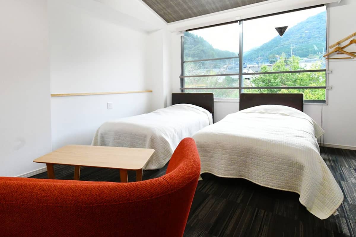 A room with two beds, a small table, and a chair.
