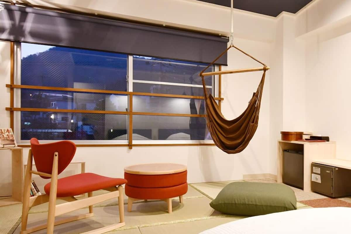 A modern room with a hanging chair, a small round table, a bed, and a window with a view.