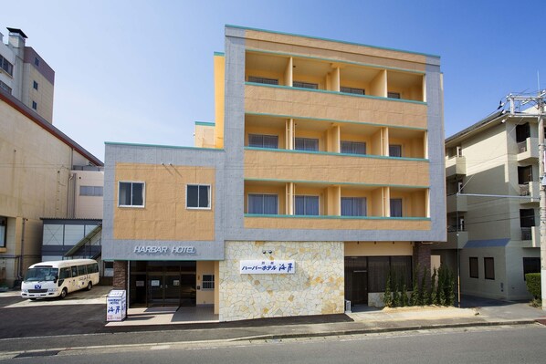 A multi-story hotel with a modern design, featuring a flat roof and a mix of beige and gray colors.