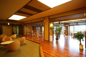 A spacious lobby with wooden flooring, comfortable seating, and large windows allowing natural light. - Bokai Hotel (Beppu)