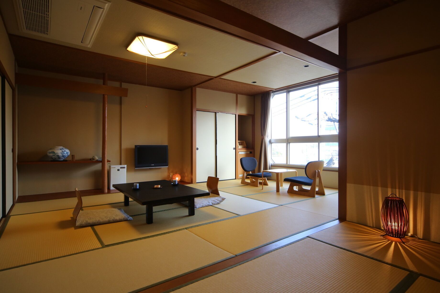 A traditional Japanese room with tatami flooring, a low table, a TV, and sliding doors.